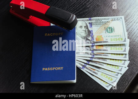 Draufsicht des Reisepasses mit Dollarnoten und Hefter auf Holztisch. Stockfoto