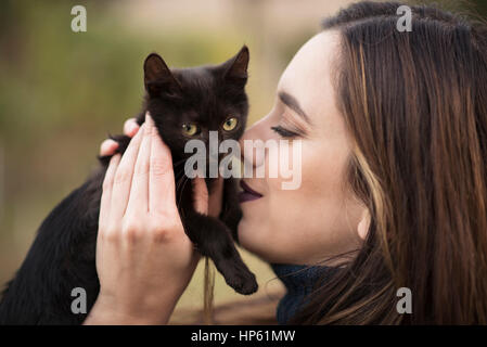 Junge hübsche Frau Kuscheln mit einer schwarzen Katze Stockfoto