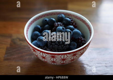 Blaubeeren und Brombeeren in einer roten und weißen Schüssel Stockfoto