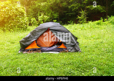 Blick auf Zelt auf der Wiese im Wald. Camping Hintergrund. Camping und Zelt. Tourist-Zelt im Wald mit Sonnenstrahlen am Campingplatz. Camping im Naturpark in su Stockfoto