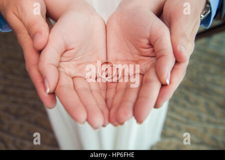 Zwei goldene Hochzeit Ringe auf Braut und Bräutigam seine Handflächen. Trauringe auf der Handfläche. Braut und Bräutigam halten Hochzeit Ringe auf ihren Handflächen während eines Engagements Stockfoto