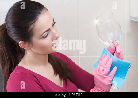 junge schöne Frau Hausfrau Blick auf perfekte gewaschenes Glas. Küche-Frau. Junge Frau in Küche, Hausarbeit, reinigen Sie das Glas. Frau-Feuchttücher Stockfoto