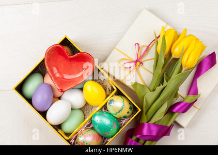 Bunte Ostereier und Tulpen in schöner Geschenkbox mit Bändern dekoriert Stockfoto