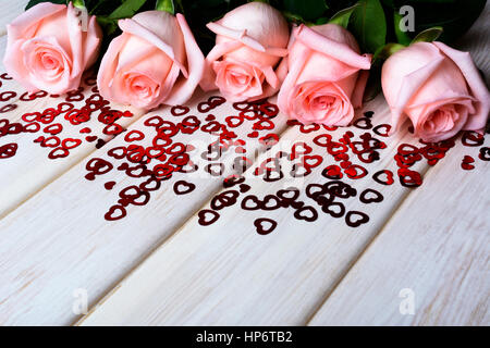 Verlieben Sie sich in Liebe Konzept mit blass rosa Rosen und kleinen roten Herzen. Elegante Hochzeitseinladung. Valentinstag Grußkarten-Hintergrund. Kopieren Sie Raum. Stockfoto