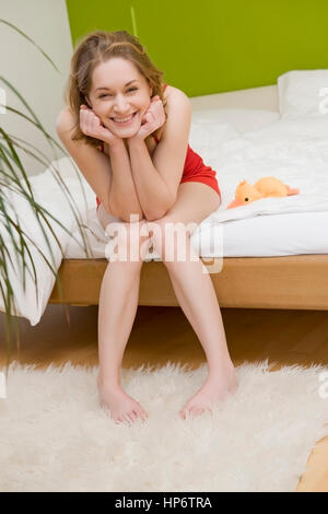 Model Release, Junge, Rutschelefanten Frau, 25 +, Sitzt Lachend Auf Bettkante - junge, lachende Frau im Schlafzimmer auf dem Bett sitzend Stockfoto