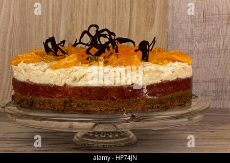 Frische orange Kuchen mit Mascarpone, Gelee, orange Partikel und fördern Bitterschokolade, geschichtet steht auf dem Typenschild auf einem alten Holztisch. Stockfoto