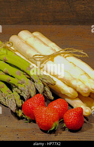 Erntefrische Spargel und Erdbeeren auf einem urigen, alten Holzbrett Stockfoto