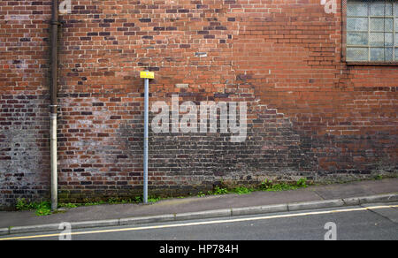 Gepatchte Mauerwerk an Wand des Industriebaus mit Parkplatz Einschränkung unterzeichnen auf der angrenzenden Straße, Burnley, Lancashire, UK Stockfoto