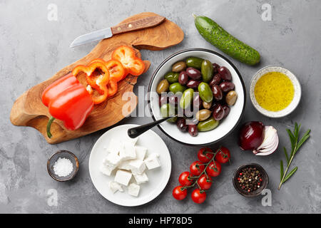 Griechischer Salatzutaten: frische Oliven, Feta-Käse, Tomaten, Paprika, Gurken und Olivenöl auf Stein Hintergrund Stockfoto