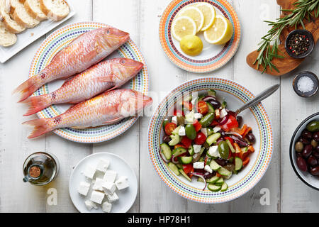 Rohe Meeräsche Fisch, griechischen Salat und anderen mediterranen Zutaten auf weißer Holztisch Stockfoto