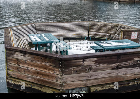 Ein Blick auf einem Rastplatz auf dem Wasser mit Bänken und Tischen. Schuss getroffen im Coulon Park in Renton, Washington. Stockfoto