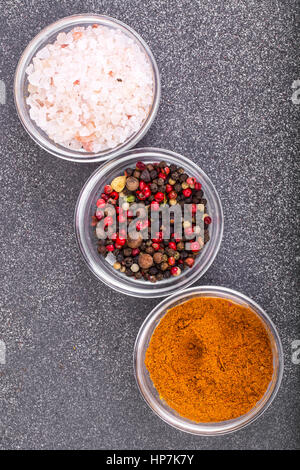 Verschiedene trockene Gewürze, Saucen und Getreide in Glasformen auf Grund des grauen Stein. Studio Photo Stockfoto