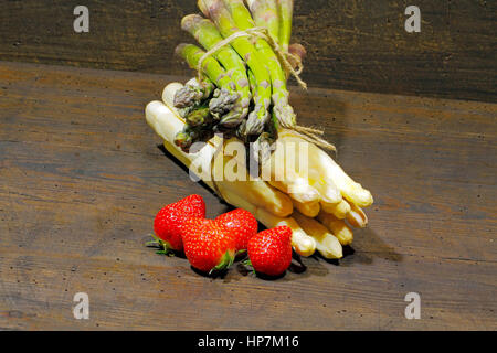 Erntefrische Spargel und Erdbeeren auf einem urigen, alten Holzbrett Stockfoto