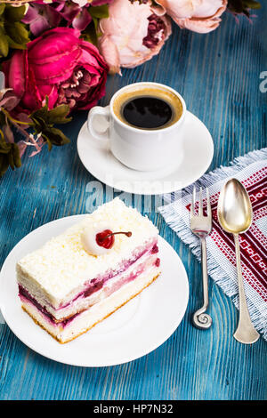 Stück Kuchen, Kuchen, Sahne, Kirschen, Schlagsahne auf blauem Hintergrund. Studio Photo Stockfoto