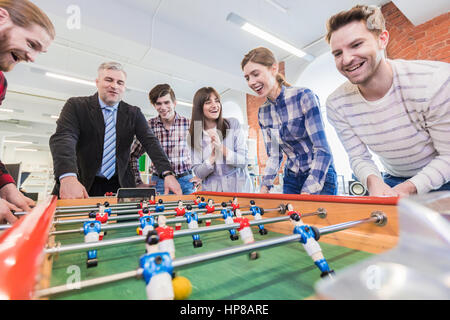 Mitarbeiter spielen Tischfußball indoor Spiel im Büro während der Pausenzeit Stockfoto