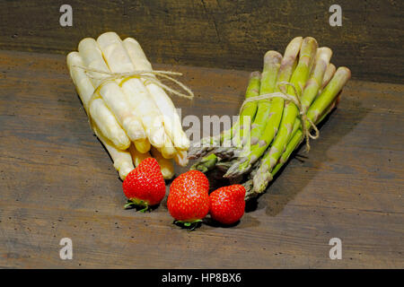 Erntefrische Spargel und Erdbeeren auf einem urigen, alten Holzbrett Stockfoto