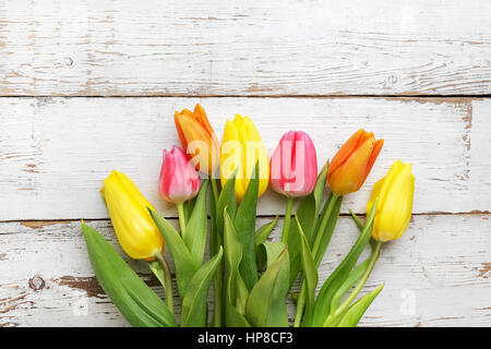 Orange, rosa und gelbe Tulpen auf einem alten weißen hölzernen Hintergrund Stockfoto