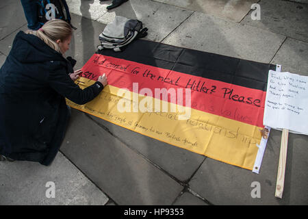 London, UK. 20. Februar 2017. Ein Demonstrant schreibt Nachrichten auf eine deutsche Flagge, wie Menschen in Parliament Square zur Verteidigung sammeln Migranten gegen US-Präsident Donald Trump kommende Staat zu besuchen, das Vereinigte Königreich Verdienst: Amer Ghazzal/Alamy Live-Nachrichten Stockfoto