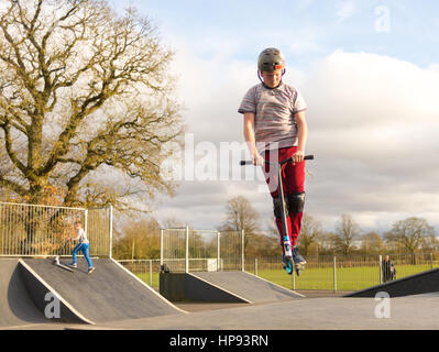 Junge, der Akrobatik auf einem Roller in einem Skatepark macht Stockfoto