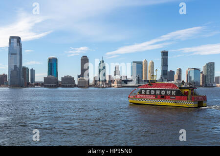 NY Waterway Fähre fährt das World Financial Center Ferry Terminal, mit der Skyline von Jersey City im Hintergrund über den Hudson River. Stockfoto