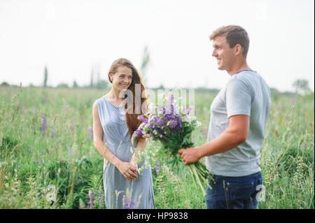 Mann gibt einer Frau einen Strauß Wildblumen auf einem Spaziergang Stockfoto