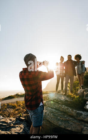 Im Freien Schuss der junge Mann seine Freunde in Landschaft beim Wandern zu fotografieren. Wanderer-Gruppe während der Sommerferien genießen. Stockfoto