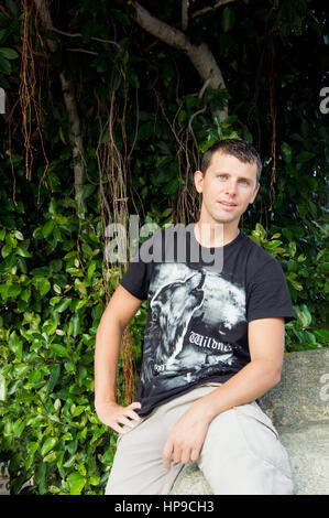 Entspannte attraktive lächelnder Mann sitzen auf Felsen. Stockfoto