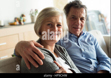 Senior paar sitzt auf einer Couch im Wohnzimmer Raum, umarmt Stockfoto