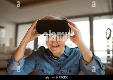 Ältere Frau mit virtual-Reality Brille zu Hause Stockfoto