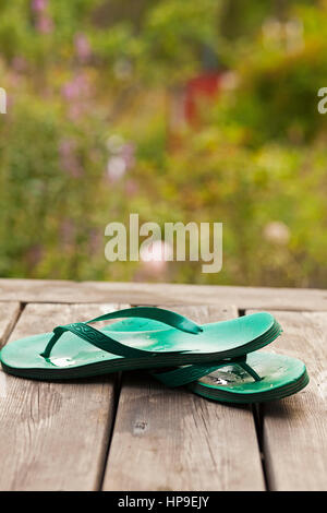 Flip flops auf der Veranda mit Blick auf einen Garten. Stockfoto