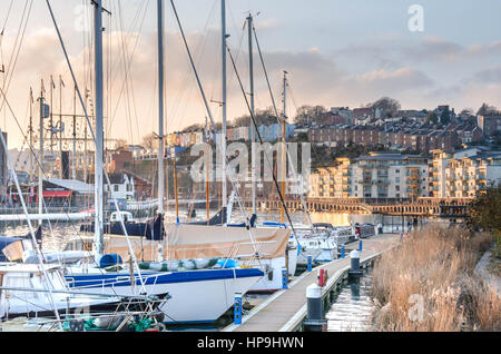 Boote im Hafen von Bristol... Schilf und Gräser ermutigen wachsen. Im Hintergrund sind Wohnungen und Häuser in orange Sonnenlicht getaucht. Stockfoto