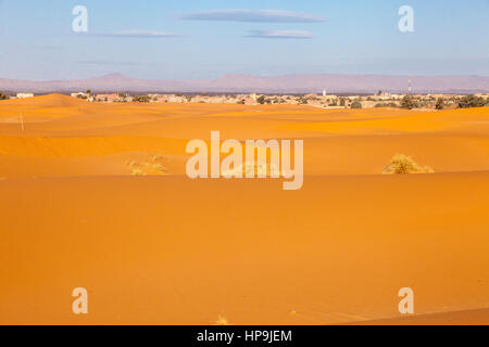 Merzouga, Marokko.  Sanddünen, Stadt im Hintergrund. Stockfoto