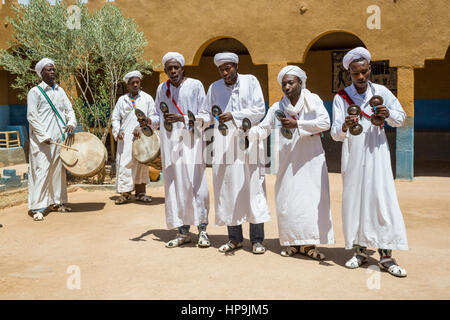 Merzouga, Marokko.  Gnaoua-Musiker spielen Krakeb und Trommeln, Durchführung traditioneller Gesang und Tanz. Stockfoto