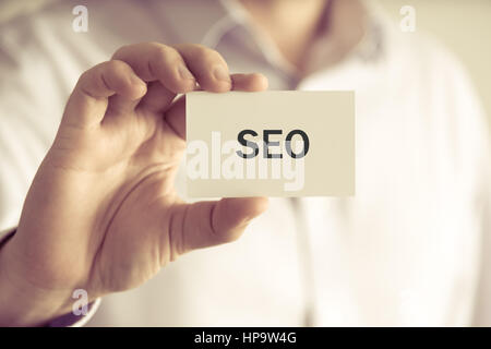 Closeup auf Geschäftsmann hielt eine Karte mit Text SEO SEARCH ENGINE OPTIMIZATION, Firmen-Konzept-Image mit soft-Fokus-Hintergrund und Vintage-Ton Stockfoto