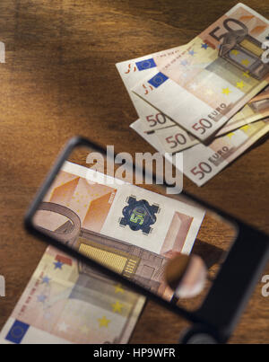 Blick durch Lupe mit 50 Euro Scheine Stockfoto