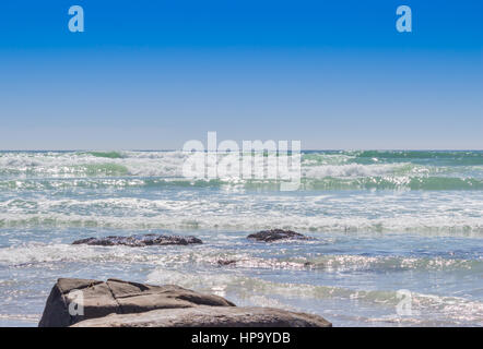 Schimmernden blauen Meereswellen mit flachen Felsen - Ozean Strand Hintergrund mit Text-Raum Stockfoto