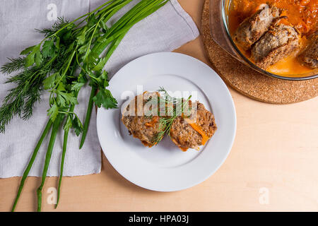 Frikadelle aus Schweinefleisch serviert auf einem weißen Teller und Kräuter - Dill, Frühlingszwiebeln, Petersilie um die Platte. Hausgemachte Frikadellen, gebraten mit Gemüse in Keramik Stockfoto