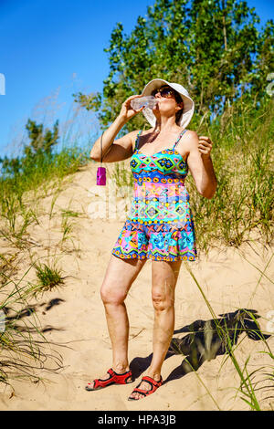 Frau ist Trinkwasser beim Wandern in den Dünen in Nord-Michigan Stockfoto