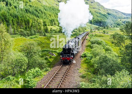 Der Jacobite Dampfzug fährt bergauf über Glenfinnan Station in Richtung Mallaig an einem sonnigen Sommertag Stockfoto