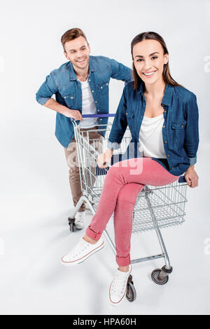 Frau sitzt auf Einkaufswagen mit Blick auf ihr Mann Stockfoto