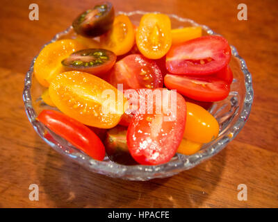 Schüssel mit gemischten kleinen Tomaten halbieren. Stockfoto