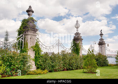 Ein kunstvoll verziertes Eisentor mit Efeu-bekleideten Steinsäulen in einem üppigen Garten, Teil des Dolmabahce-Palastes in Istanbul, Türkei. Stockfoto