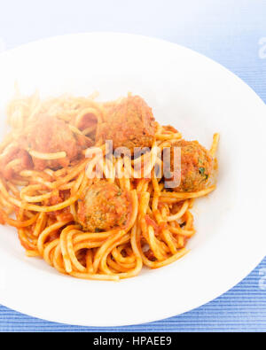 Eine Platte von zu Hause gekocht herzhaften Spaghetti und Fleischbällchen weiße Platte auf einen blauen Platzdeckchen. Stockfoto