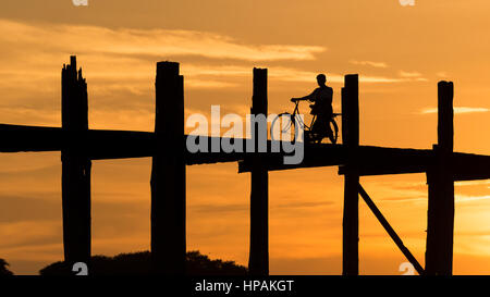 Silhouette Mann mit Fahrrad bei Sonnenuntergang auf u-Bein Brücke, die längste Teakholz Brücke der Welt Stockfoto