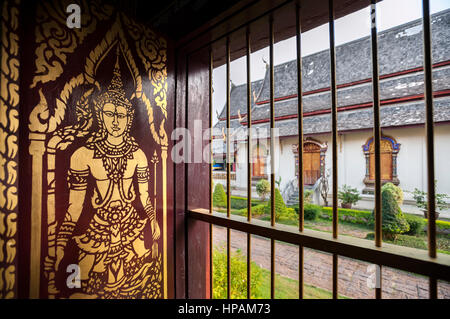 Gold-lackiert Buddha Bild auf einer hölzernen Shutter auf der Innenseite der wiharn des Wat Chiang Man, Chiang Mai, Thailand Stockfoto