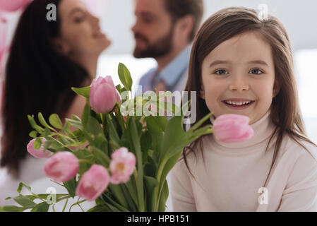 Tolle Stimmung. Entzückende süße schöne Mädchen stand in der Nähe der blumeblumenstrauß und beim Betrachten Sie lächelnd Stockfoto