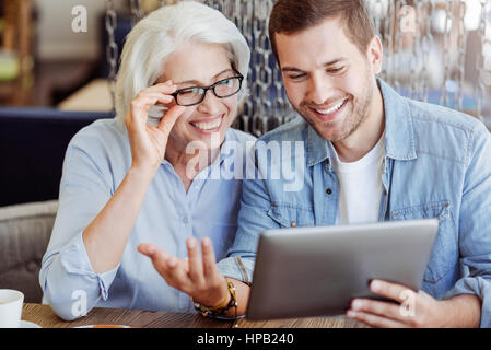 Voller Freude. Fröhliche zufrieden lächelnde Frau im Alter von Frau und ihr Enkel mit tablet Stockfoto