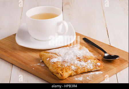Weiße Tasse heißen Tee und frische Brötchen auf alten Holztisch Stockfoto