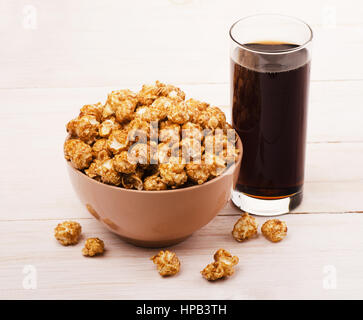 Popcorn in Schüssel mit Cola auf einem Holztisch Stockfoto