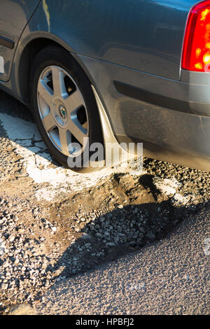 Auto-Rad über ein Schlagloch fahren / Schlagloch / Löcher / Schlaglöcher wo die Straße / Straße trifft eine Bremsschwelle / Speedbump, um den Verkehr zu verlangsamen. VEREINIGTES KÖNIGREICH. Stockfoto